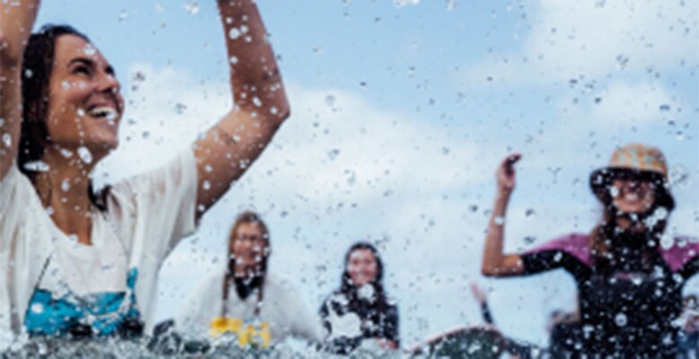 People in water smiling and splashing water upwards