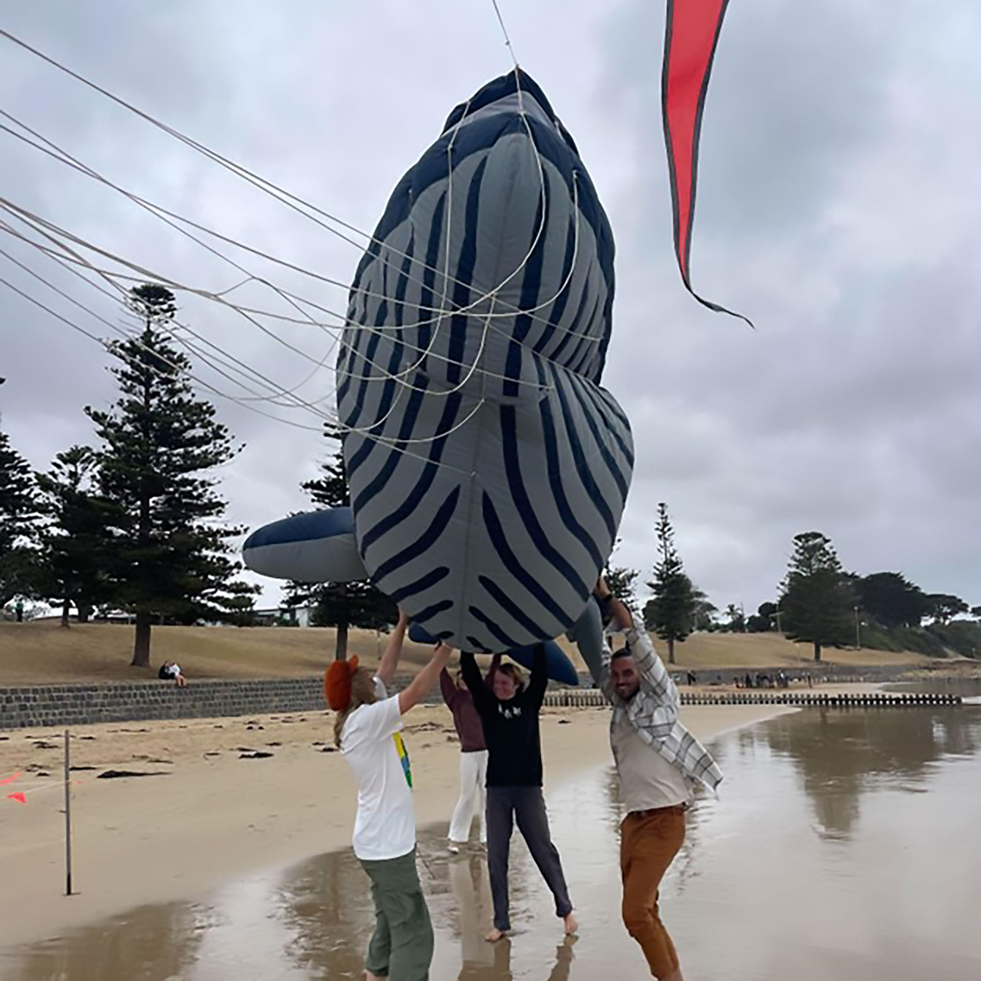 People holding up a whale shaped balloon