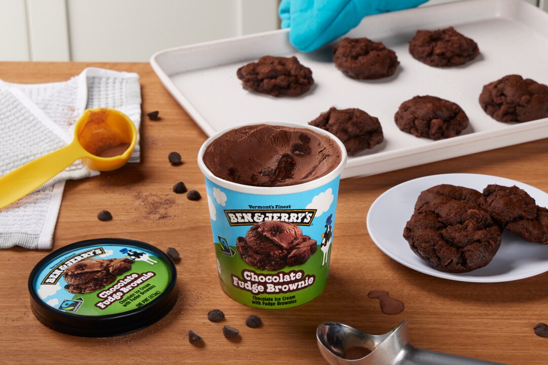 Pint of Ben & Jerry's Chocolate Fudge Brownie ice cream next to a plate of chocolate cookies on a kitchen counter