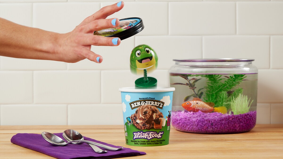 Hand removing a lid from a pint of ice cream with a toy popping out