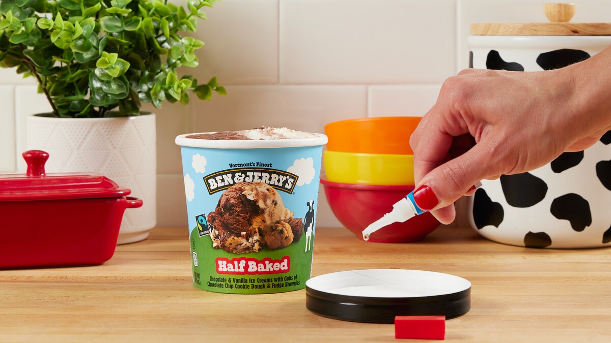 Hand dripping super glue onto the inside of an ice cream pint lid