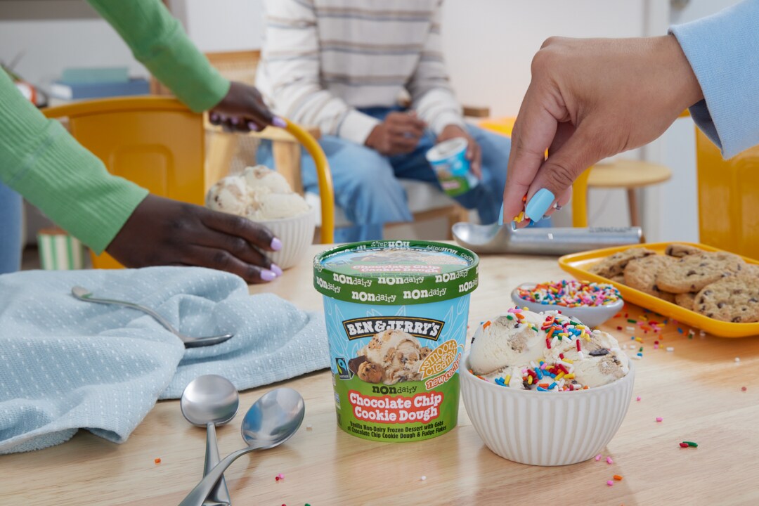 Hand adds sprinkles on top of a bowl of Ben & Jerry's Chocolate Chip Cookie Dough Non-Dairy. Pint is nearby.