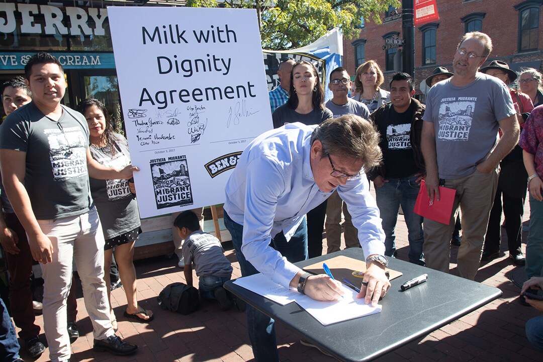Former Ben & Jerry's CEO Josein Solheim signs the Milk With Dignity agreement surrounded by Migrant Justice activists in 2017.