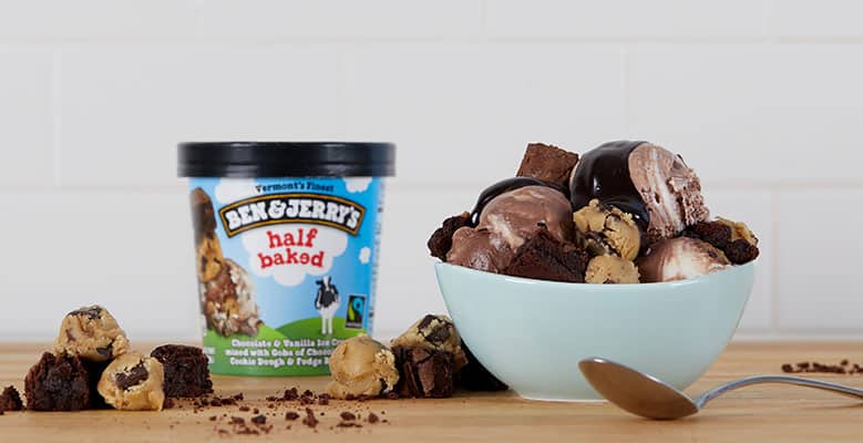 Pint of Ben & Jerry's Half Baked ice cream next to a hot fudge sundae in a bowl.