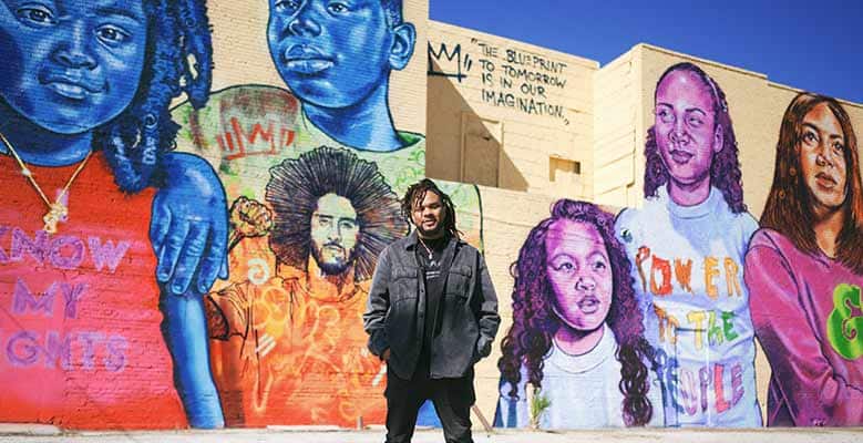 Brandan "Bmike" Odums stands in front of his mural in Old West Tampa, FL.